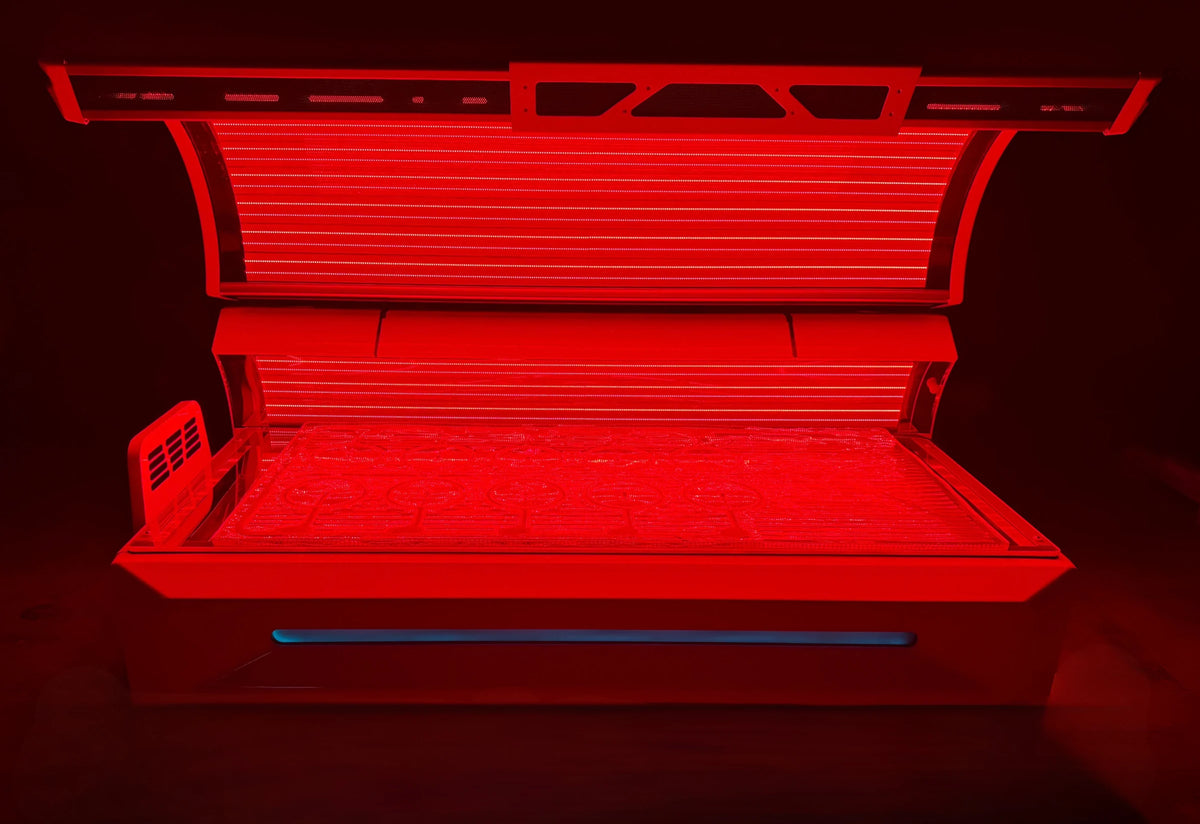 Helios Commercial red light therapy bed, lid open, with the Optix Fusion PEMF mat lit on the treatment surface