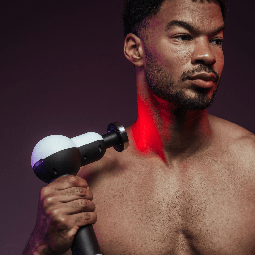 Man using Solbasium S2 Massage Gun with built-in red light therapy on neck and shoulder for muscle recovery
